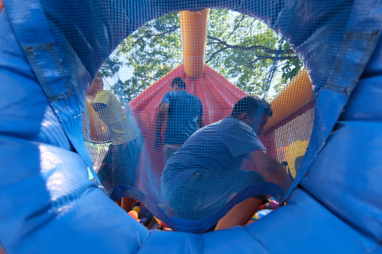 Parte interna de um inflável azul com pessoas ao fundo brincando  
